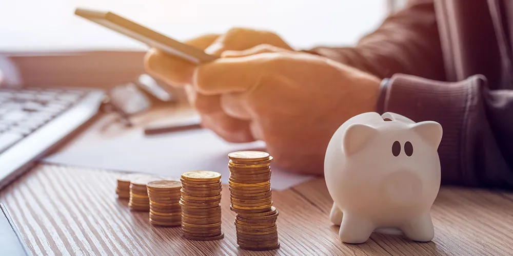 Person using a smart phone with coins on the table