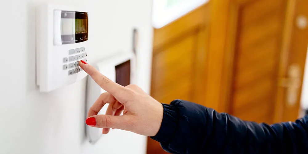 cutting-edge-solutions Person typing in the code to their modern home security system